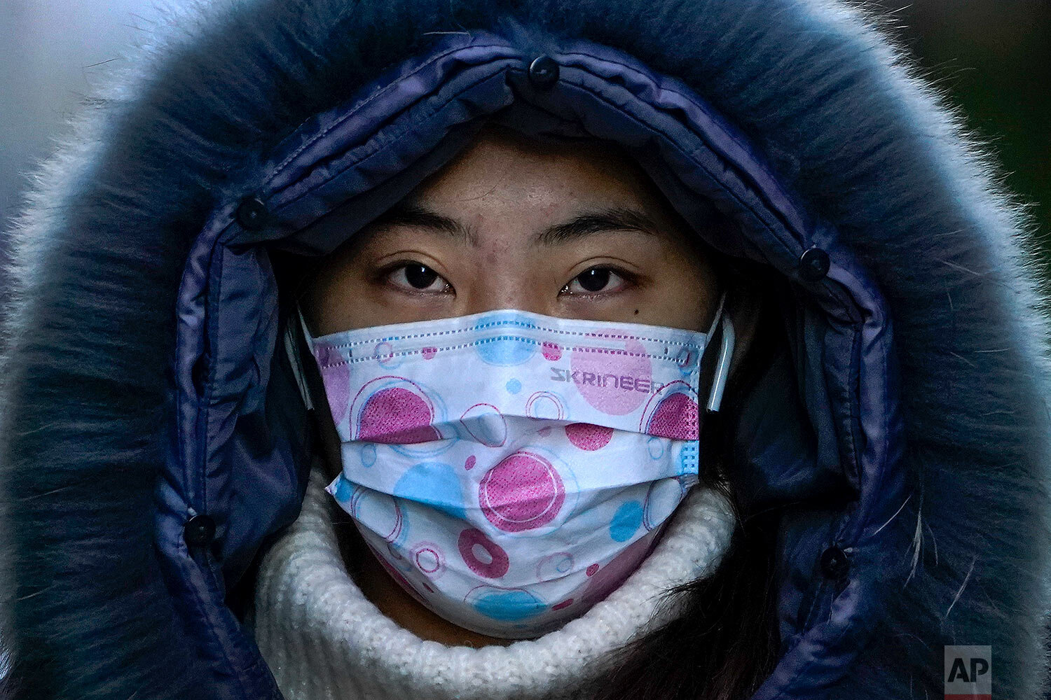  A woman, wearing a face mask to help curb the spread of the coronavirus, walks on a street during the morning rush hour in Beijing, Wednesday, Dec. 16, 2020. (AP Photo/Andy Wong) 