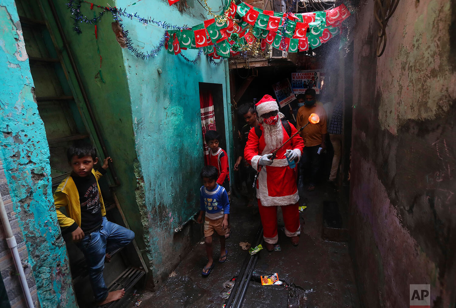  A man dressed as Santa Claus sanitizes a narrow lane in Dharavi, one of Asia's biggest slums, in Mumbai, India, Saturday, Dec. 19, 2020. (AP Photo/Rafiq Maqbool) 