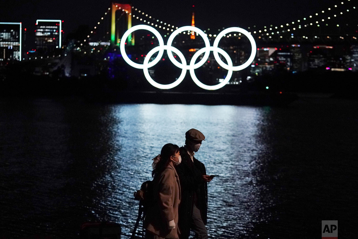  A man and a woman walk past near the Olympic rings floating in the water in the Odaiba section Tuesday, Dec. 1, 2020, in Tokyo. (AP Photo/Eugene Hoshiko) 