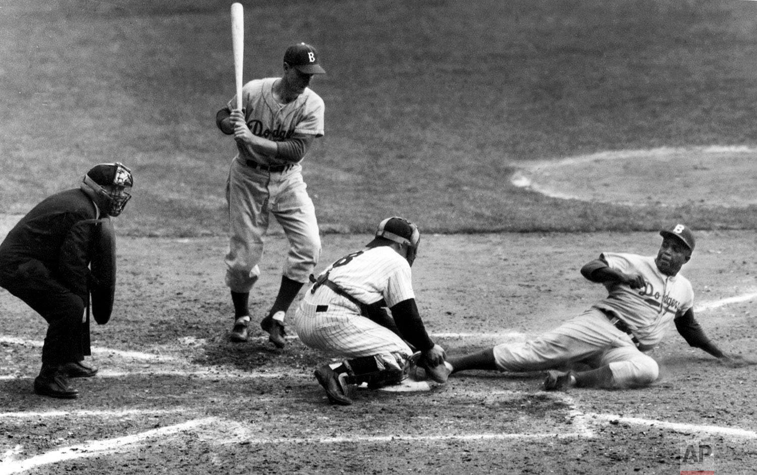  Brooklyn Dodgers' Jackie Robinson safely steals home plate under the tag of New York Yankees catcher Yogi Berra in the eighth inning of the World Series opener at New York's Yankee Stadium, Sept. 28, 1955.   (AP Photo/John Rooney) 