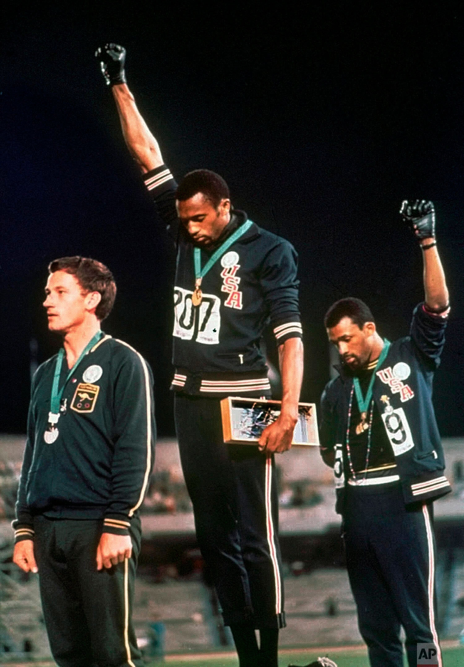  Extending gloved hands skyward in racial protest, U.S. athletes Tommie Smith, center, and John Carlos stare downward during the playing of national anthem Wednesday, Oct. 16, 1968, after Smith received the gold and Carlos the bronze for the 200 mete
