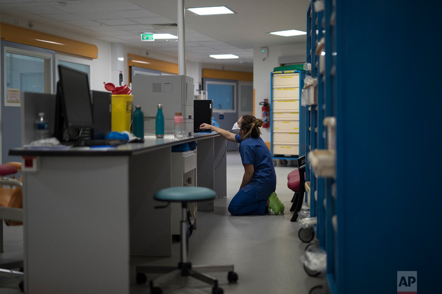  A nurse rests her knees on the floor as she looks at a computer screen during the day shift at the COVID-19 ICU of the La Timone hospital in Marseille, southern France, Thursday, Nov. 12, 2020. (AP Photo/Daniel Cole) 