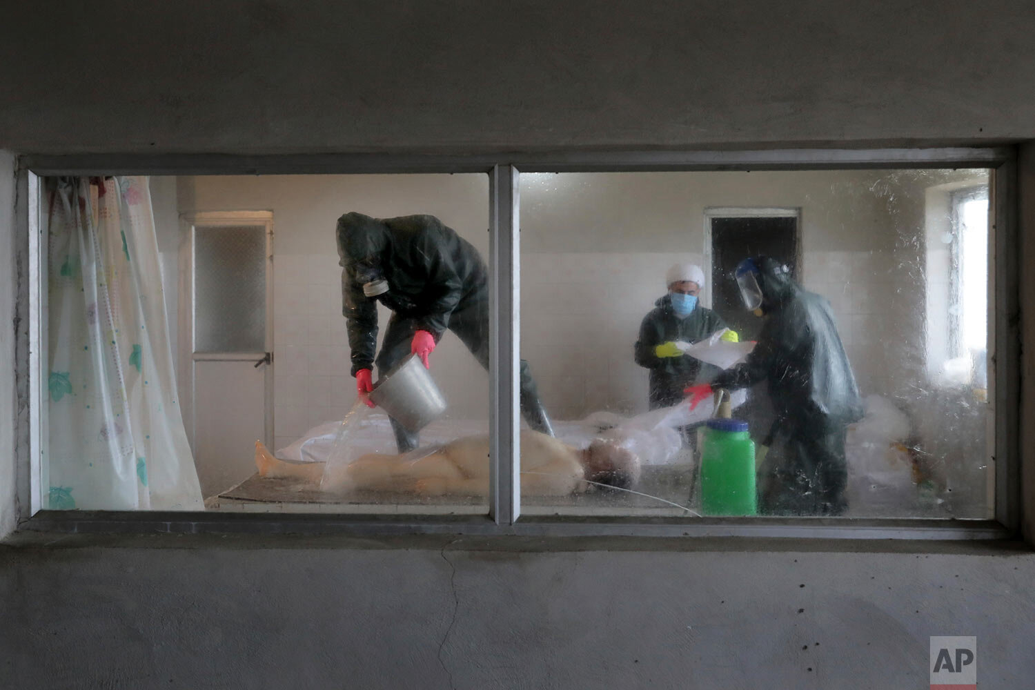  Clerics wearing protective clothing prepare the body of a man who died from COVID-19 for a funeral at a cemetery in the outskirts of the city of Ghaemshahr, in northern Iran, Saturday, Dec. 19, 2020. (AP Photo/Ebrahim Noroozi) 