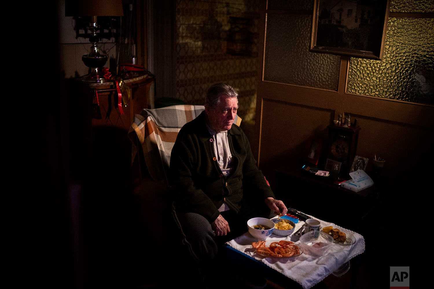  Álvaro Puig Moreno watches television while eating a his Christmas Eve dinner at his home in Barcelona, Spain, Thursday, Dec. 24, 2020. (AP Photo/Emilio Morenatti) 