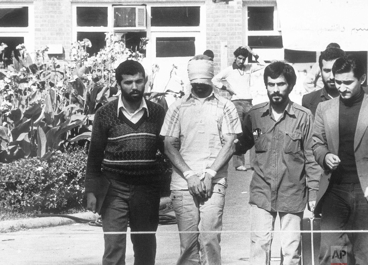  Blindfolded and hands bound, one of the hostages held at the U. S. Embassy in Tehran, Iran is shown to the crowd by Iranian students on Nov. 8, 1979. (AP Photo) 