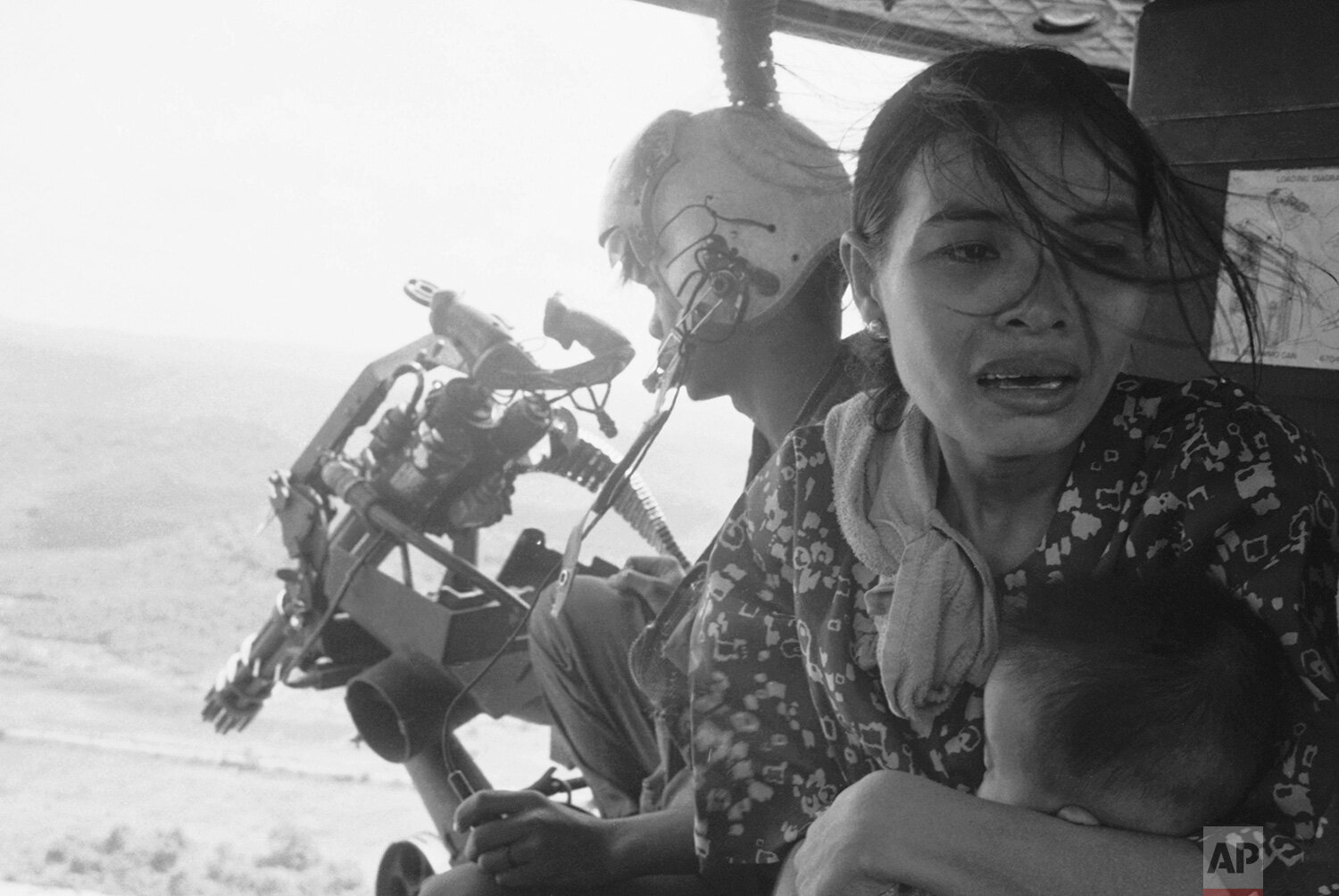  A refugee clutches her baby as a government helicopter gunship carries them away near Tuy Hoa, 235 miles northeast of Saigon on Mar. 22, 1975.  (AP Photo/ Nick Ut) 