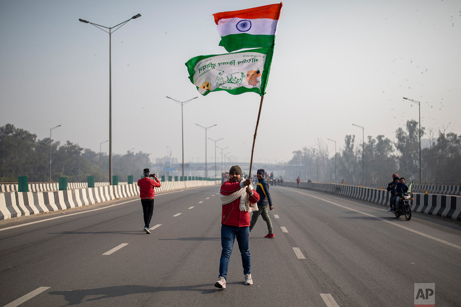 A protesting farmer waves an Indian flag and a farmer union flag as he marches with others to the capital breaking police barricades during India's Republic Day celebrations in New Delhi, India, Tuesday, Jan. 26, 2021. (AP Photo/Altaf Qadri) 