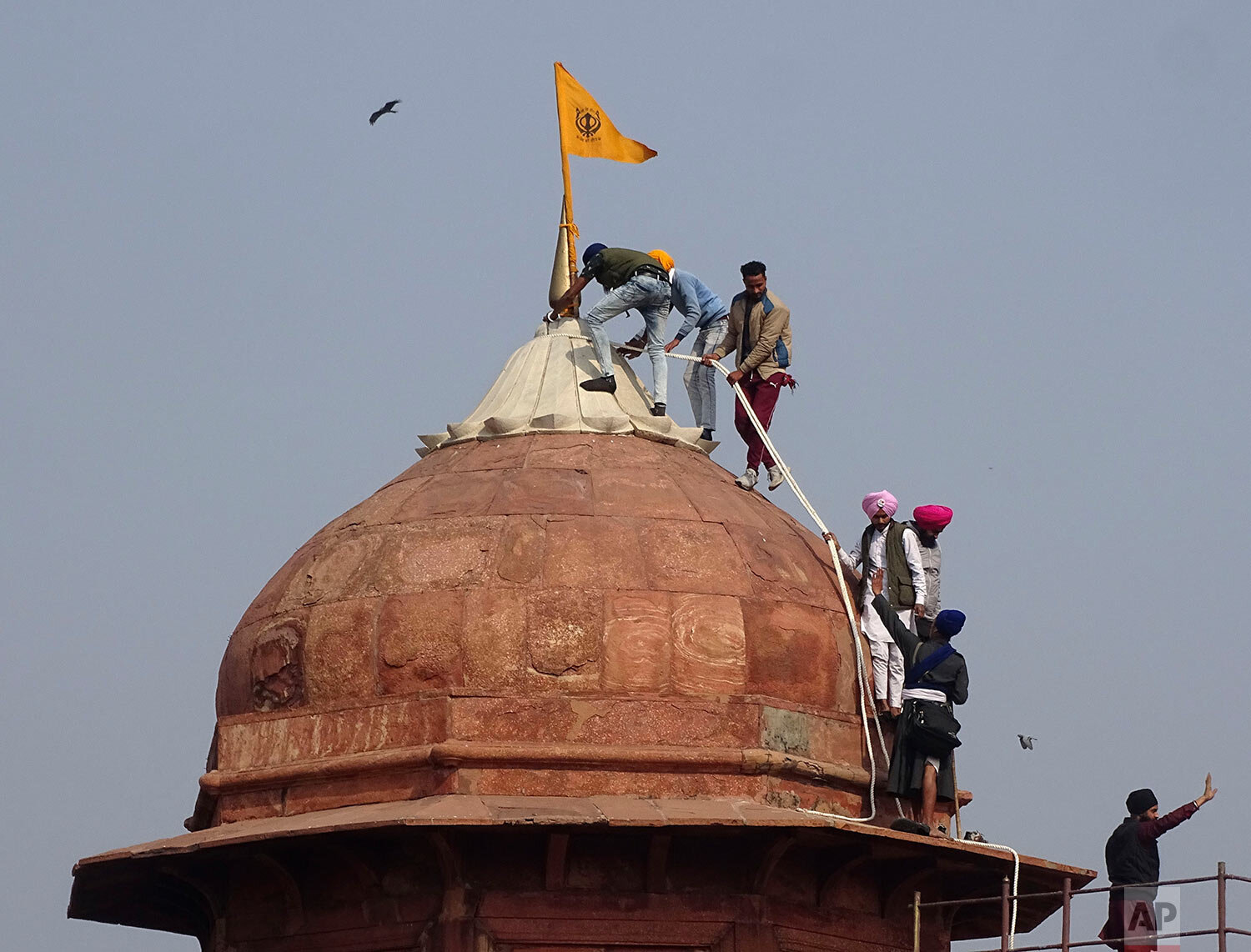  Sikhs hoist a Nishan Sahib, a Sikh religious flag, on a minaret of the historic Red Fort monument in New Delhi, India, Tuesday, Jan. 26, 2021. (AP Photo/Dinesh Joshi) 
