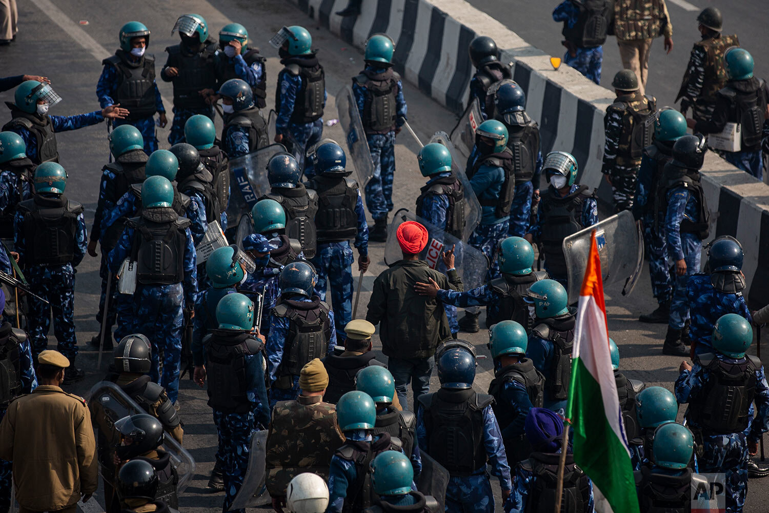  A protesting farmer, wearing orange turban, is let go by riot police as they march to the capital breaking police barricades during India's Republic Day celebrations in New Delhi, India, Tuesday, Jan. 26, 2021.  (AP Photo/Altaf Qadri) 