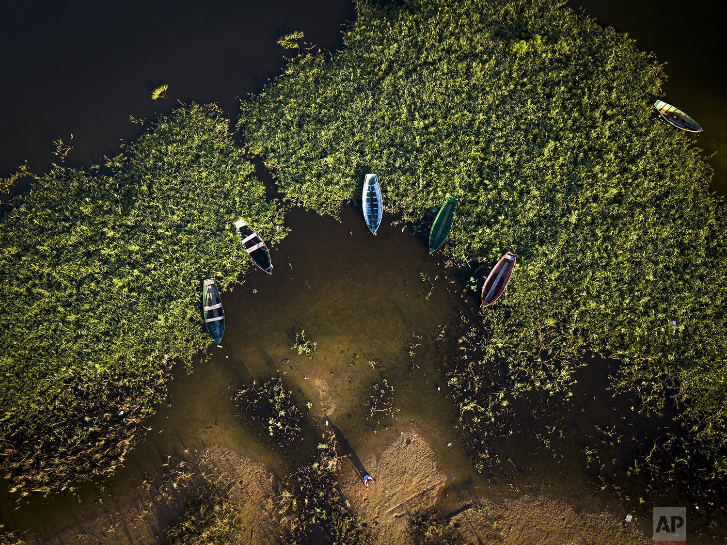  Boats sit idle as a fisherman, standing bottom center, prepares to go out to the Bay of Asuncion, Paraguay, Jan. 8, 2021. (AP Photo/Jorge Saenz) 