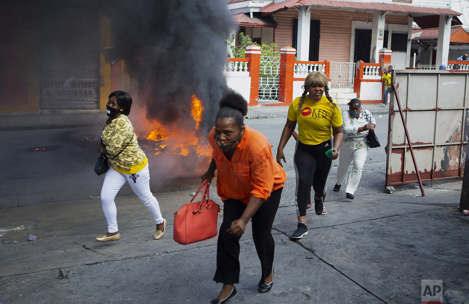  People run past a a barricade set fire by protesters demanding President Jovenel Moise resign in Port-au-Prince, Haiti, Jan. 15, 2021 (AP Photo/Joseph Odelyn) 