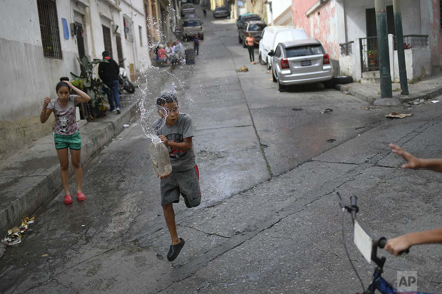  A boy prepares to playfully drench a friend with a water in the Amparo neighborhood of Caracas, Venezuela, Jan. 21, 2021, amid the COVID-19 pandemic. (AP Photo/Matias Delacroix) 