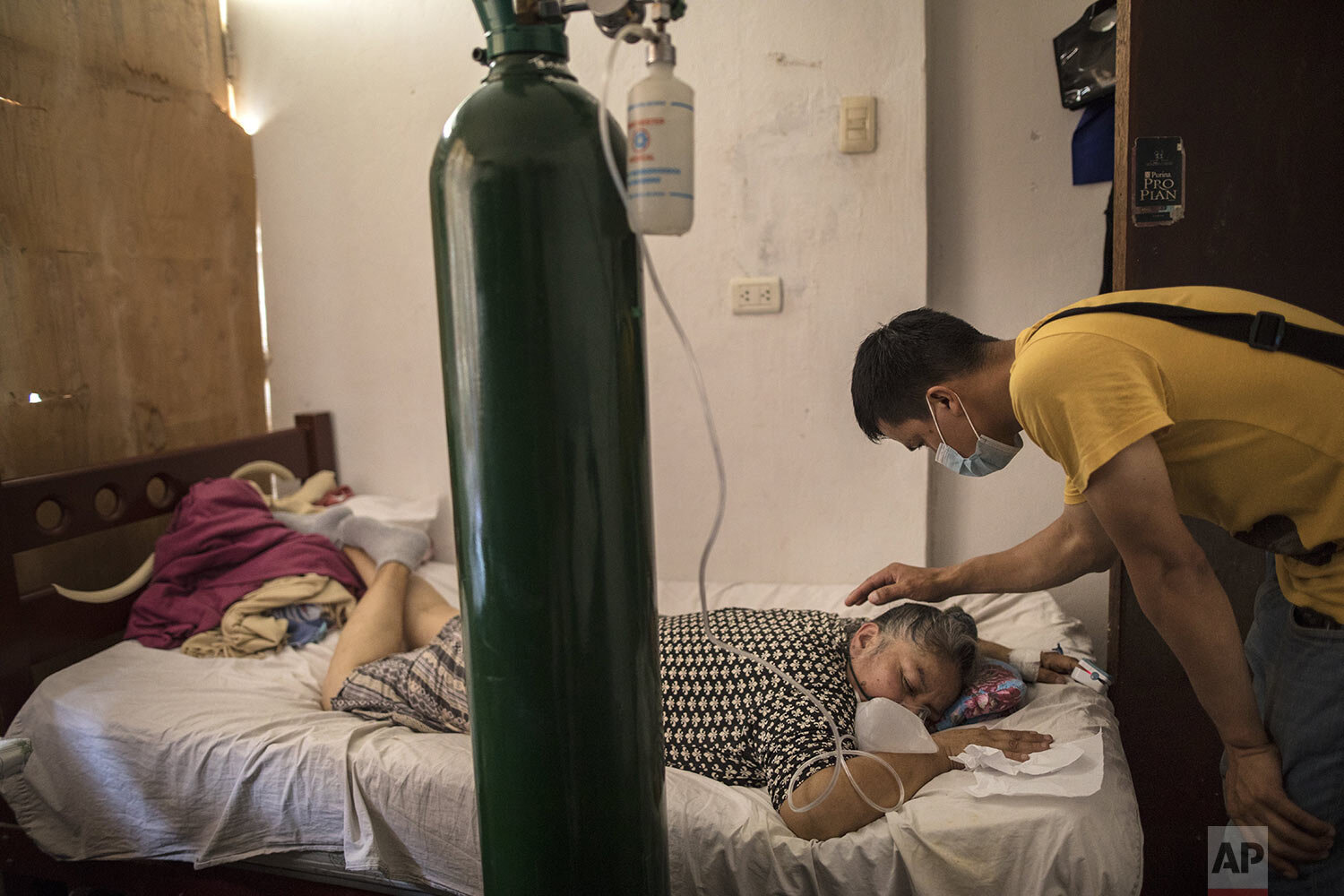  Elena Ruiz, 53, breathes in oxygen as part of her recovery treatment for COVID-19 as her son Antony watches over her in Lima, Peru, Jan. 29, 2021. (AP Photo/Rodrigo Abd) 