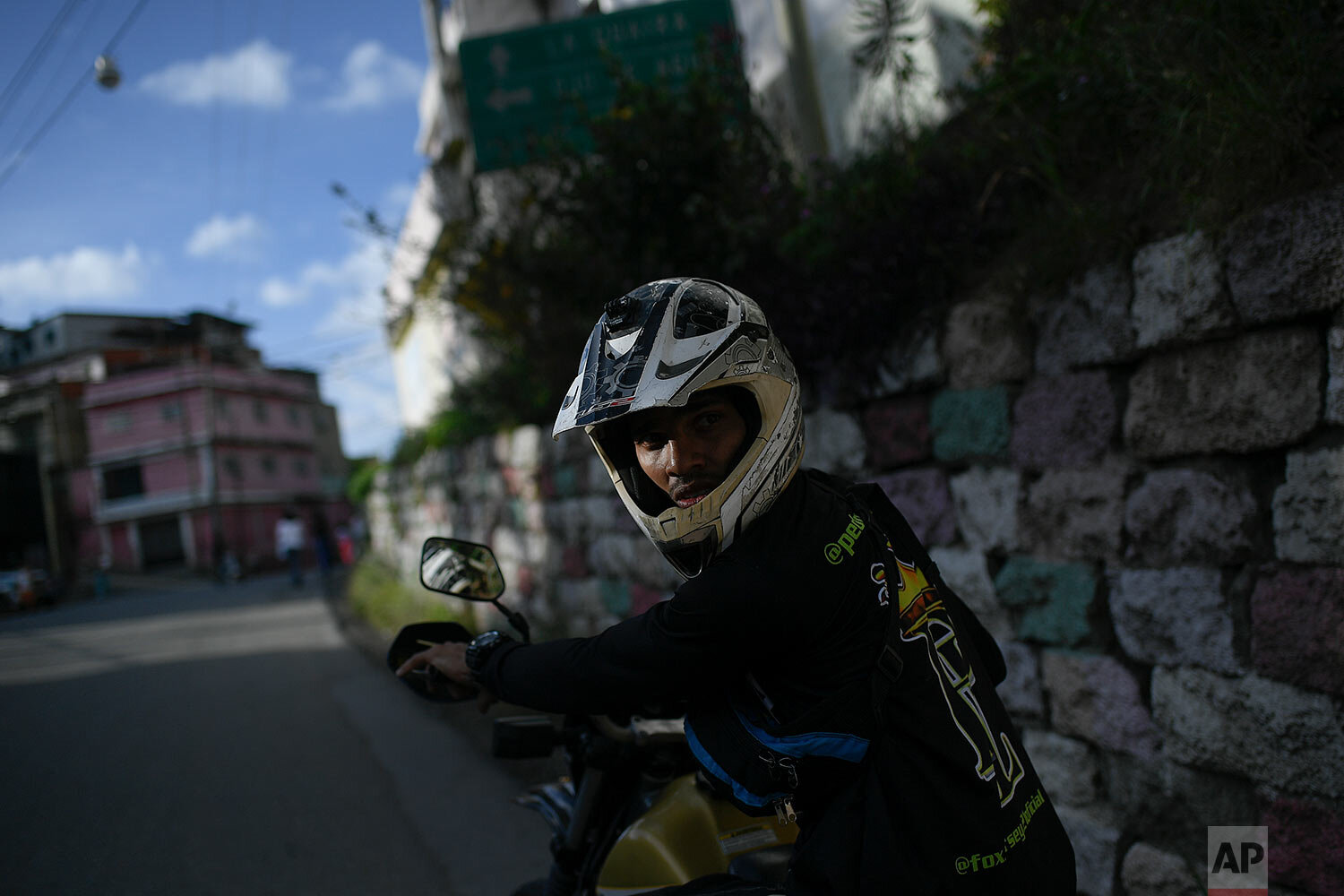  Motorcycle stuntman Pedro Aldana waits for his friends for an exhibition in the Ojo de Agua neighborhood of Caracas, Venezuela, Sunday, Jan. 10, 2021. (AP Photo/Matias Delacroix) 