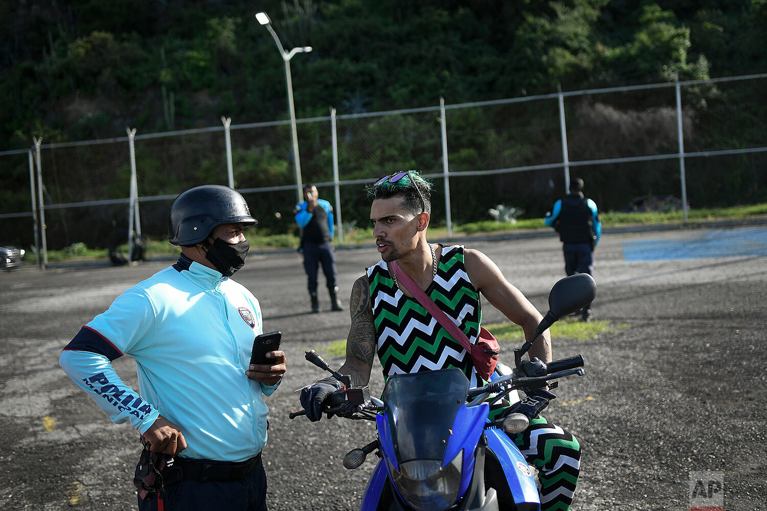  Motorcycle stuntman Pedro Aldana speaks with a police officer after officers stopped his previously authorized exhibition, citing COVID-19 restrictions, on Camuri Chico beach in La Guaira, Venezuela, Saturday, Jan. 30, 2021. (AP Photo/Matias Delacro