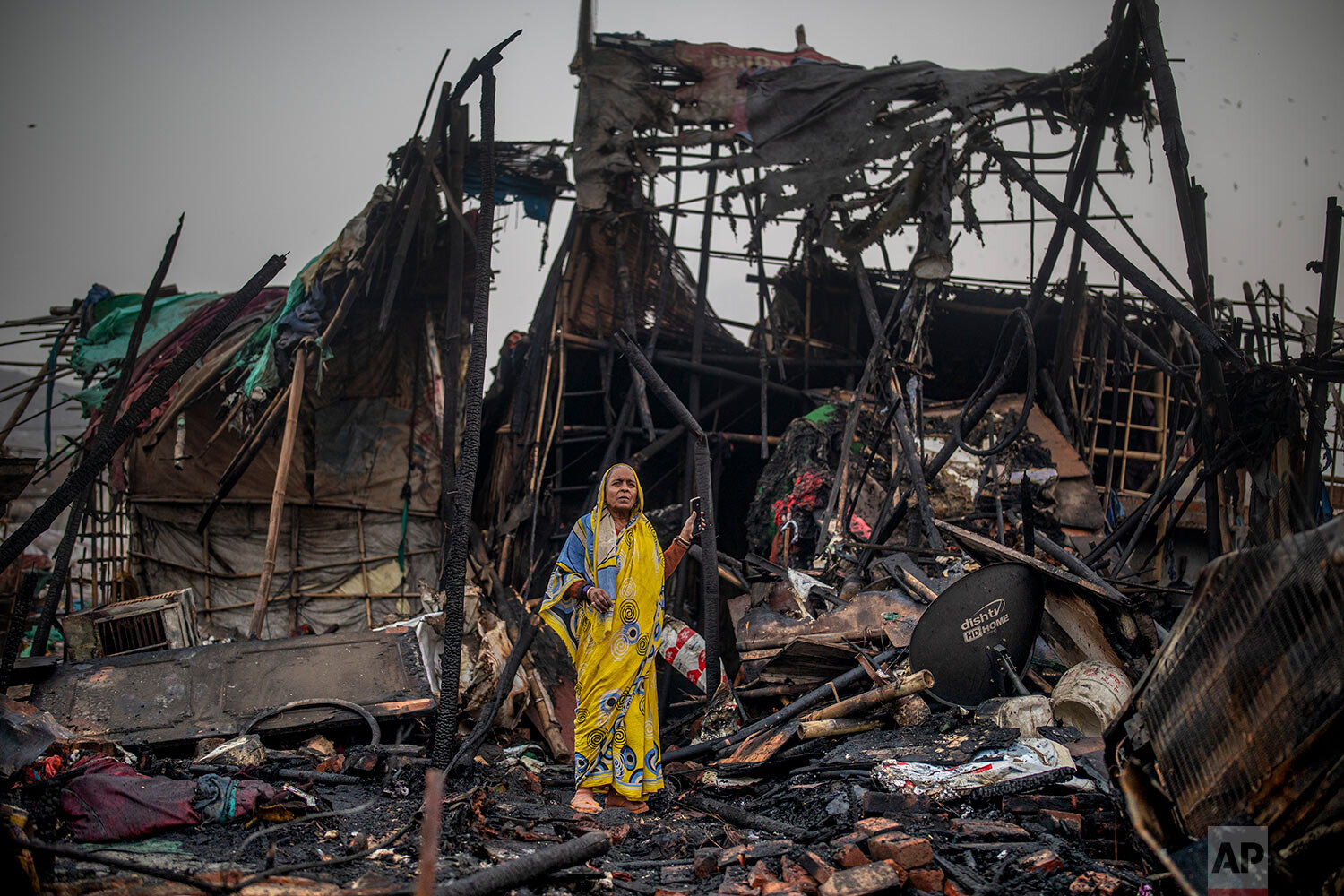  A woman stands on the debris of a fire at a slum area in New Delhi, India, Saturday, Jan. 23, 2021. More than 50 huts of a slum inhabited mostly by ragpickers were gutted in a fire that broke out Saturday afternoon.  (AP Photo/Altaf Qadri) 