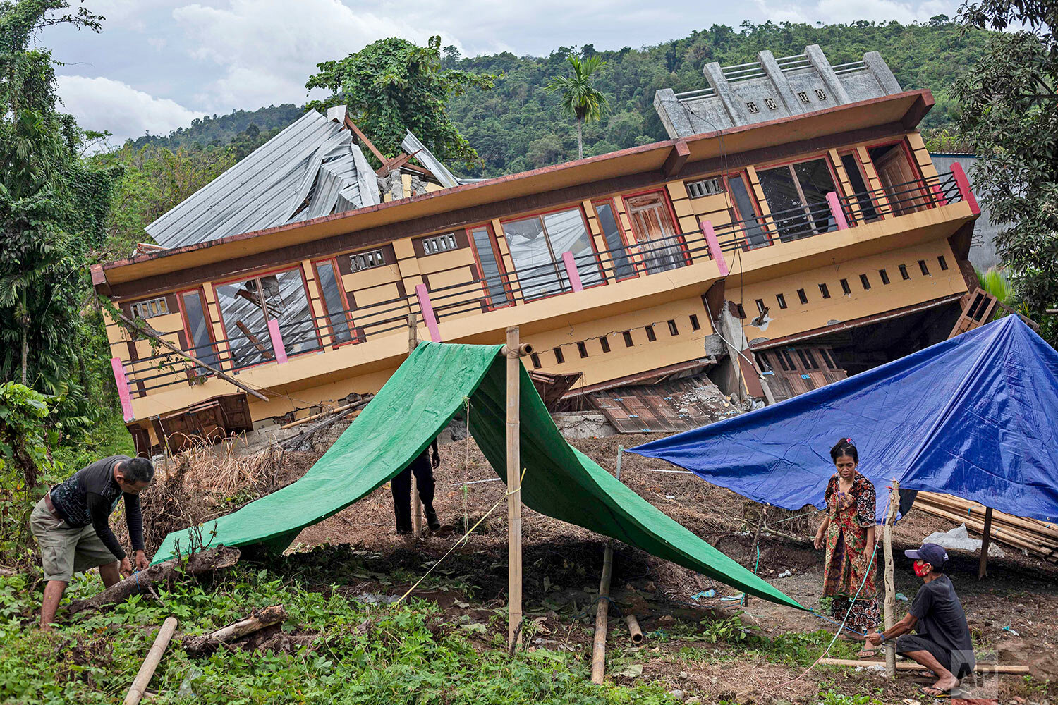  Residents build tents outside their house badly damaged by earthquake in Mamuju, West Sulawesi, Indonesia, Tuesday, Jan. 19, 2021.  (AP Photo/Yusuf Wahil) 
