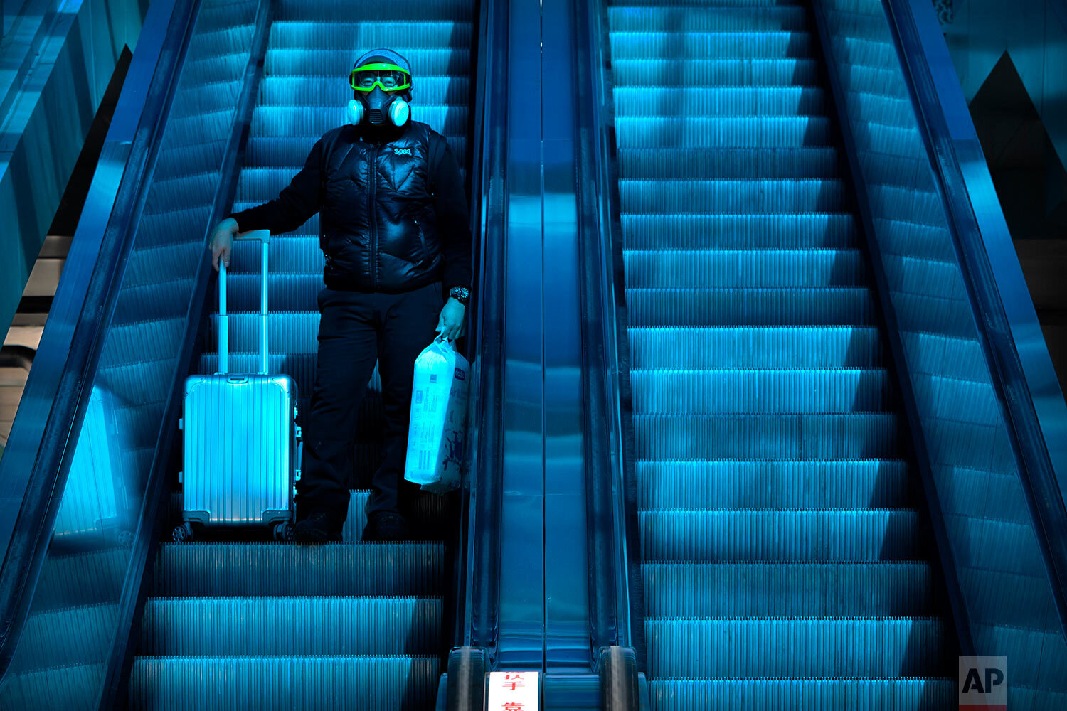  A traveler wearing a mask to protect against the spread of the coronavirus rides an escalator beneath a colored skylight at the Beijing Railway Station in Beijing, Thursday, Jan. 28, 2021.  (AP Photo/Mark Schiefelbein) 