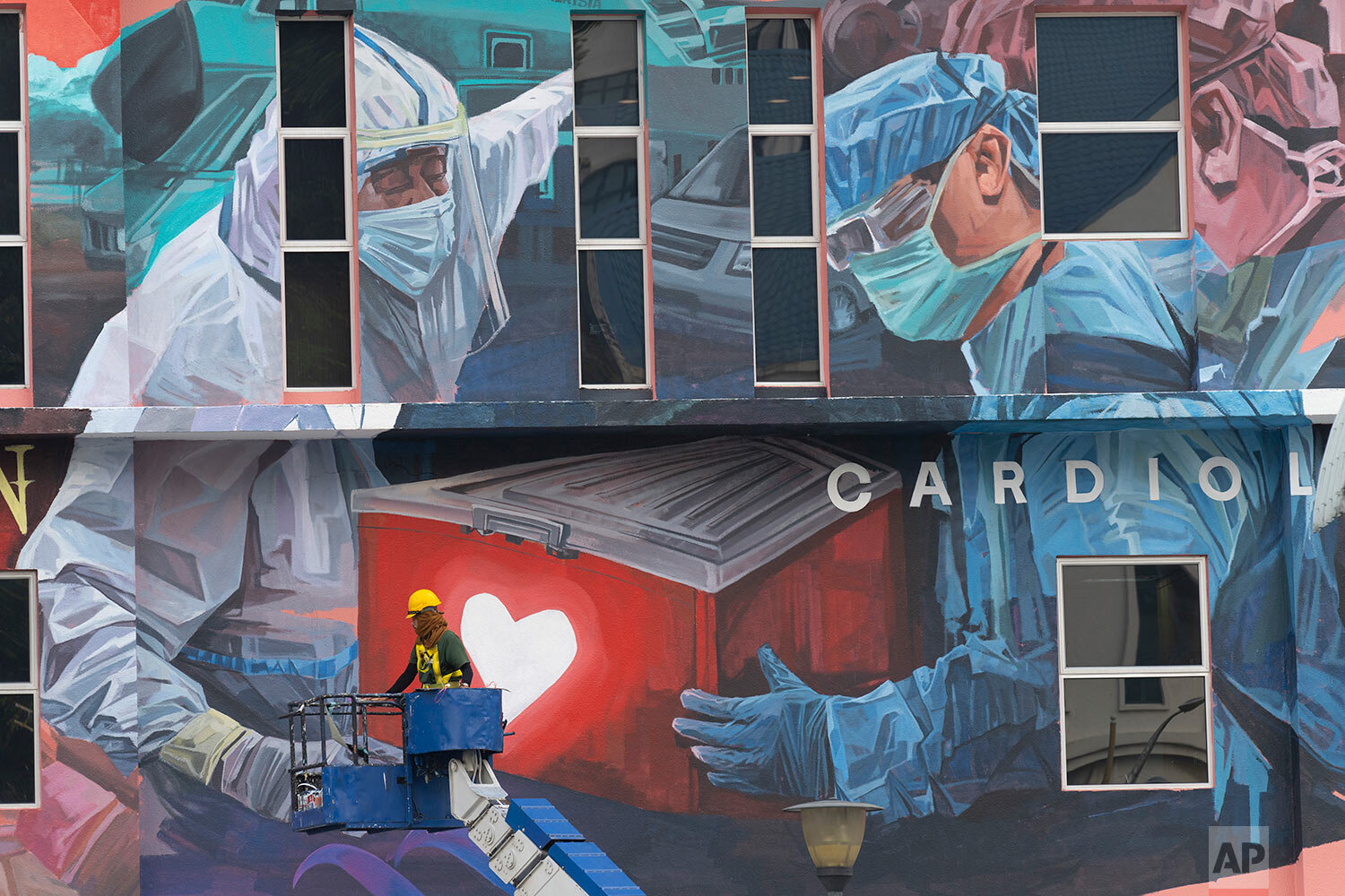  A worker adds finishing touches to giant mural tribute to frontline workers in the COVID-19 coronavirus pandemic outside a hospital in Kuala Lumpur, Malaysia, on Thursday, Jan. 21, 2021.  (AP Photo/Vincent Thian) 