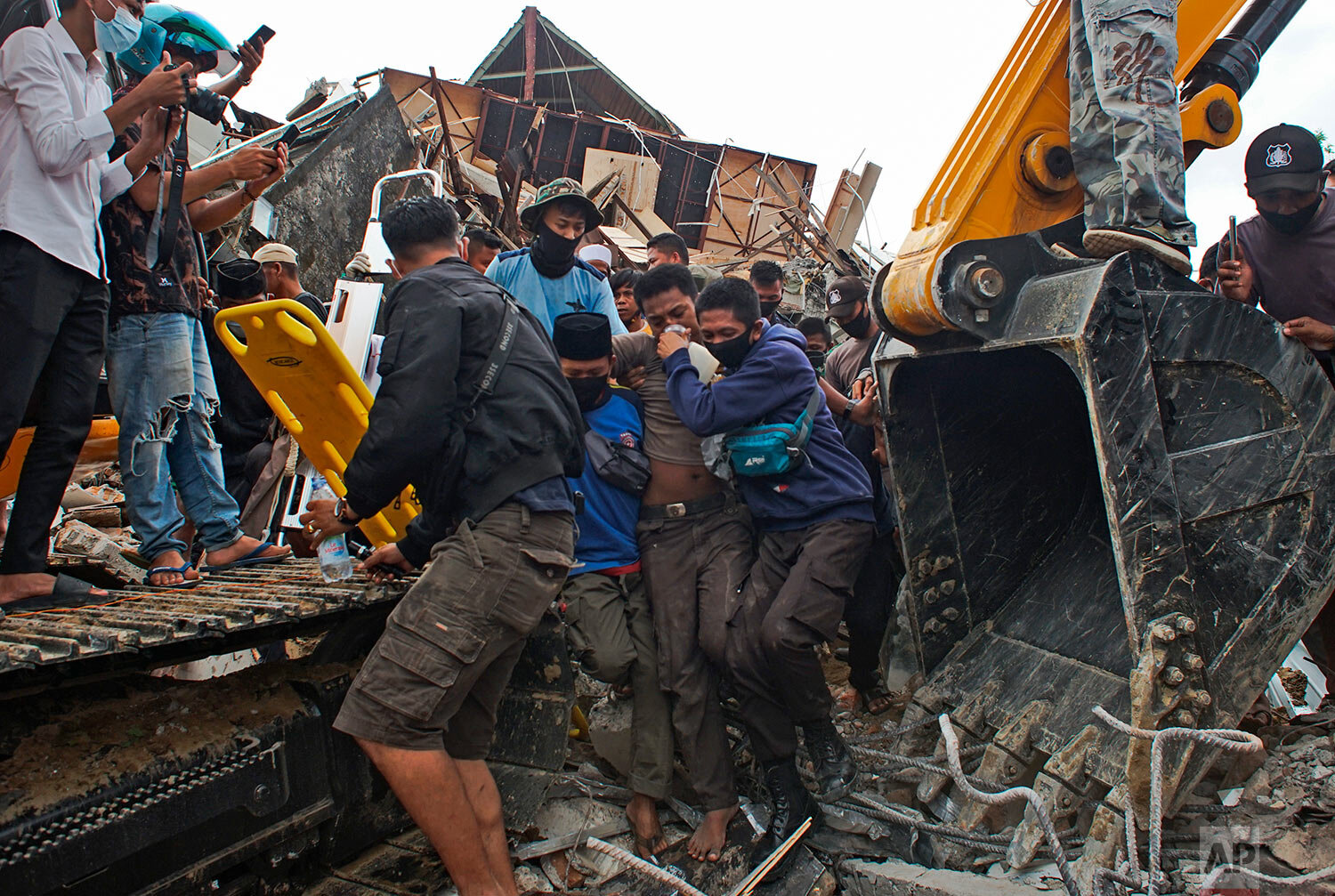  Rescuers assist a survivor pulled out from the ruin of a government building collapsed during an earthquake in Mamuju, West Sulawesi, Indonesia, Friday, Jan. 15, 2021.  (AP Photo/Azhari Surahman) 