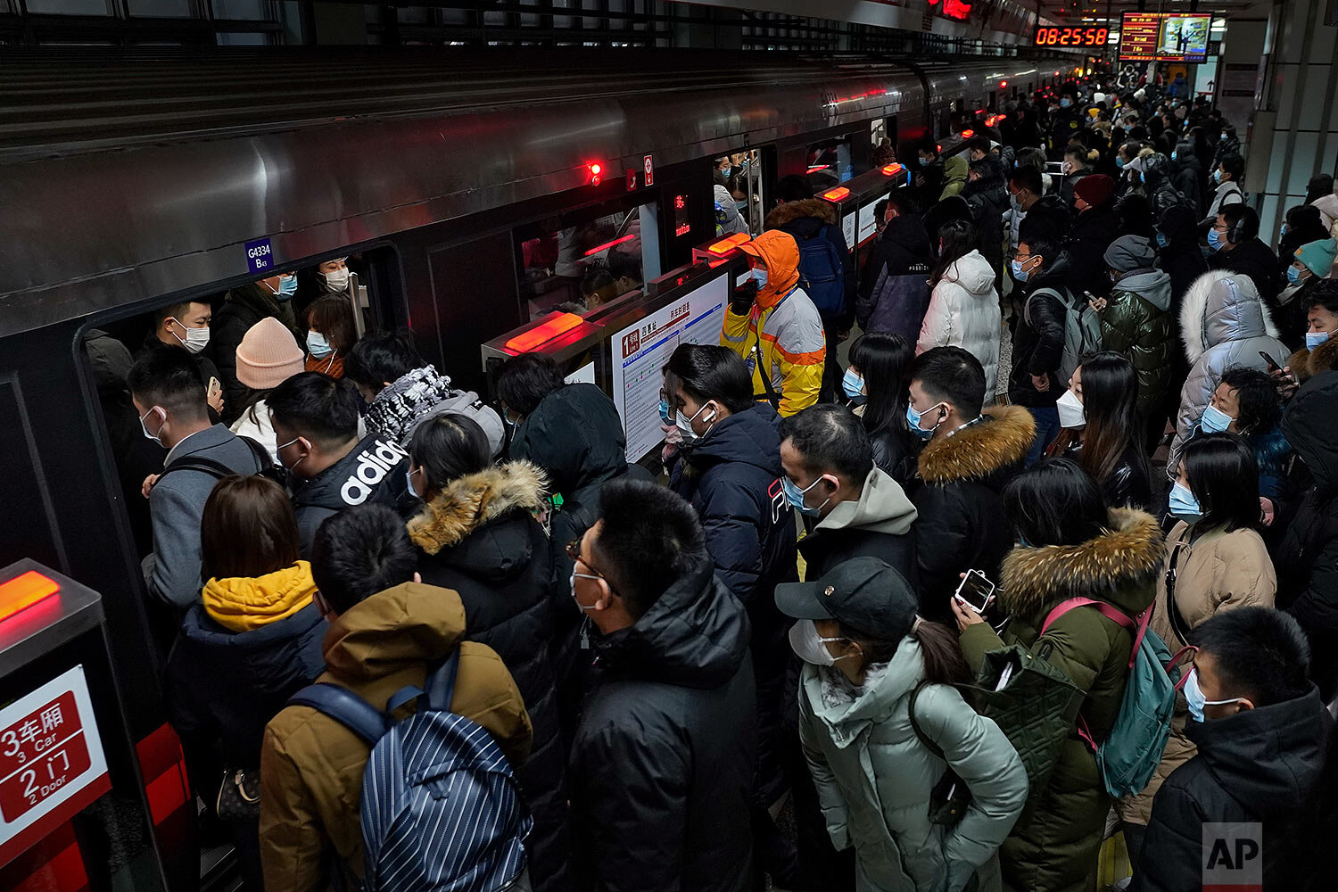  Commuters wearing face masks to help curb the spread of the coronavirus rush into a train carriage during a morning rush hour at a subway station in Beijing, Tuesday, Jan. 5, 2021.  (AP Photo/Andy Wong) 