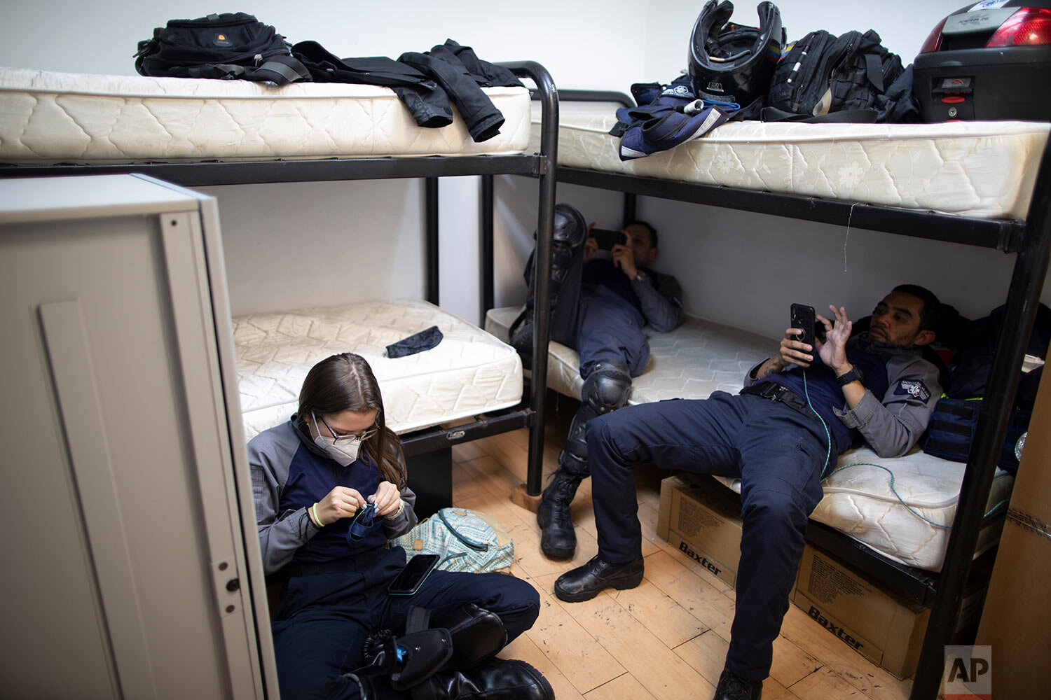  Wearing masks as a precaution against the new coronavirus, Angels of the Road volunteer paramedics Laura Lara, from left, Alexander Barreto and Bran Cabello, relax in the only room they have at their operations base in Caracas, Venezuela, Monday, Fe