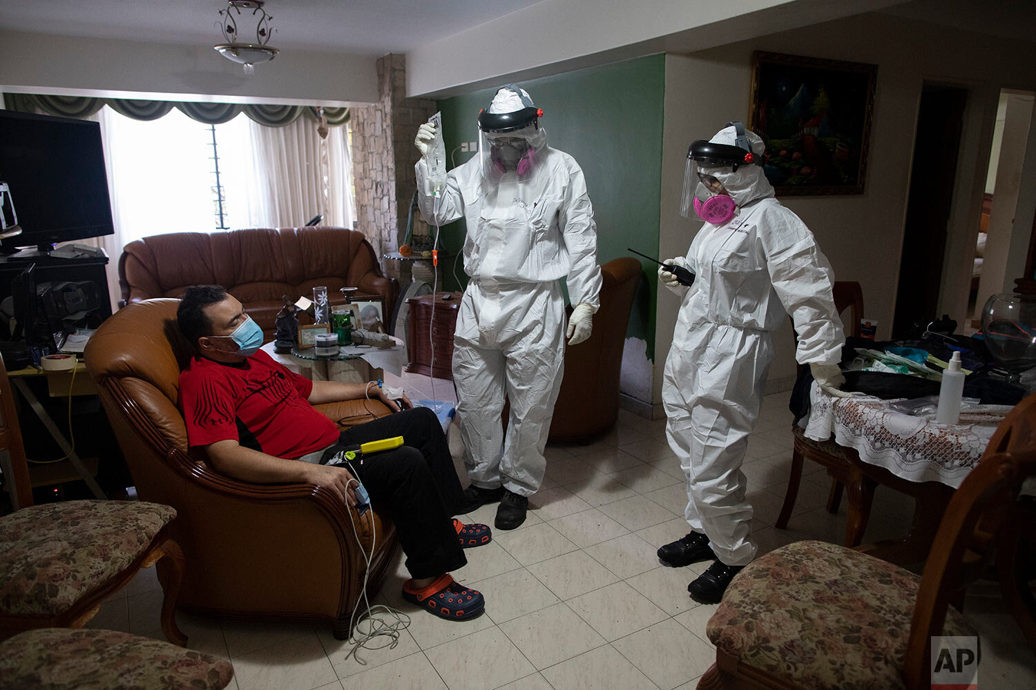  Angels of the Road volunteer paramedic Zully Rodiz, right, and Dr. Brayan Alfaro, measure the vital signs readings of a person suspected of having COVID-19, at his home in Caracas, Venezuela, Thursday, Feb. 11, 2021. (AP Photo/Ariana Cubillos) 