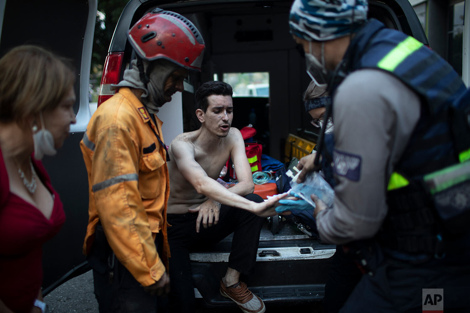  Angels of the Road volunteer paramedics tend to a man's injuries after his car caught fire at a parking lot in Caracas, Venezuela, Monday, Feb. 8, 2021. (AP Photo/Ariana Cubillos) 