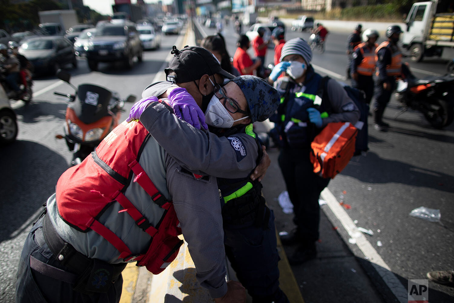  Wearing a mask as a precaution against the new coronavirus, Angels of the Road volunteer paramedic Zully Rodiz, right, hugs a paramedic who works with the Ministry of Transportation, at the scene of a traffic accident on a main highway in Caracas, V