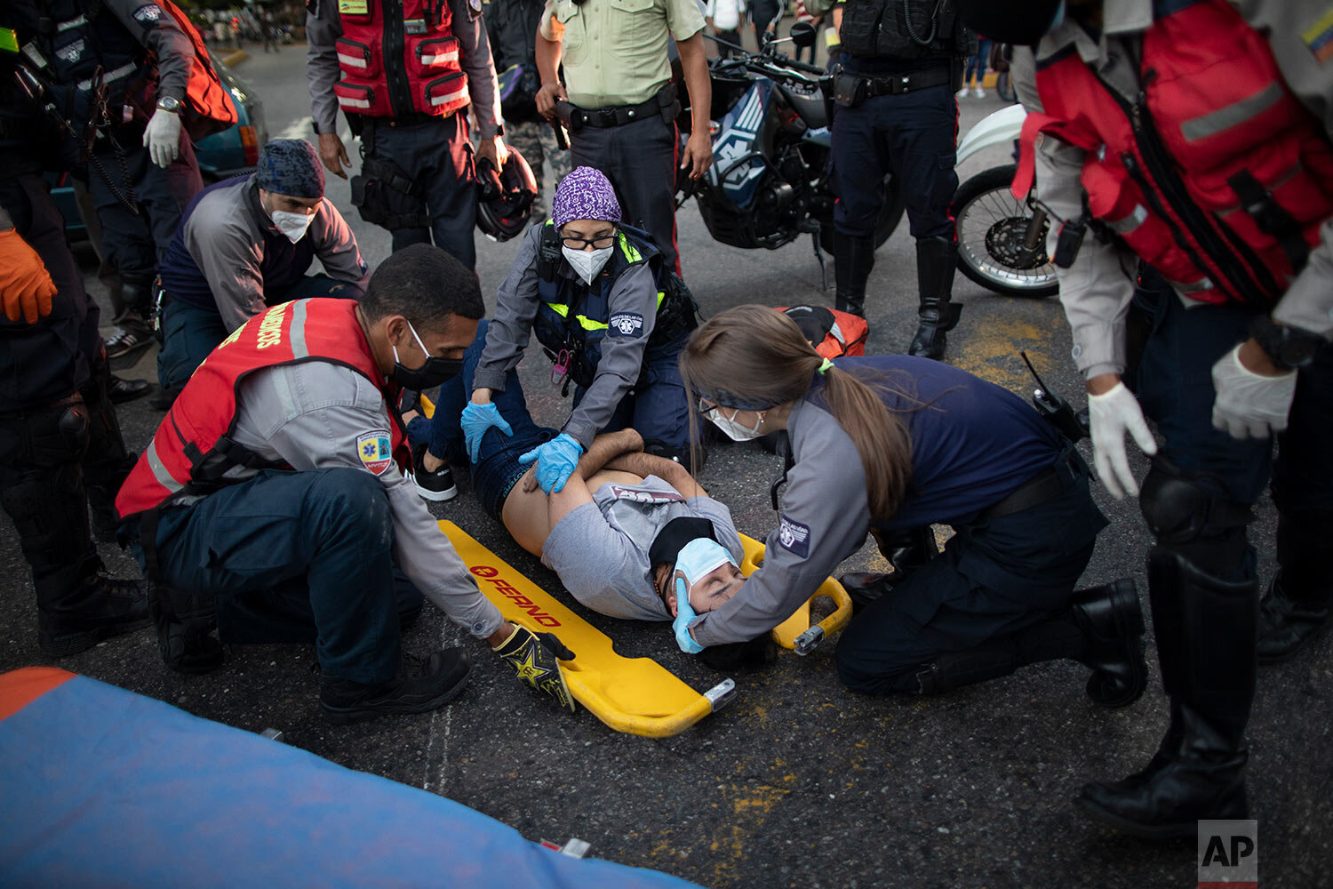  Wearing masks as a precaution against the new coronavirus, Angels of the Road volunteer paramedics, in grey and blue uniforms, place a motorcycle accident victim onto a scoop stretcher, in Caracas, Venezuela, Monday, Feb. 8, 2021. (AP Photo/Ariana C