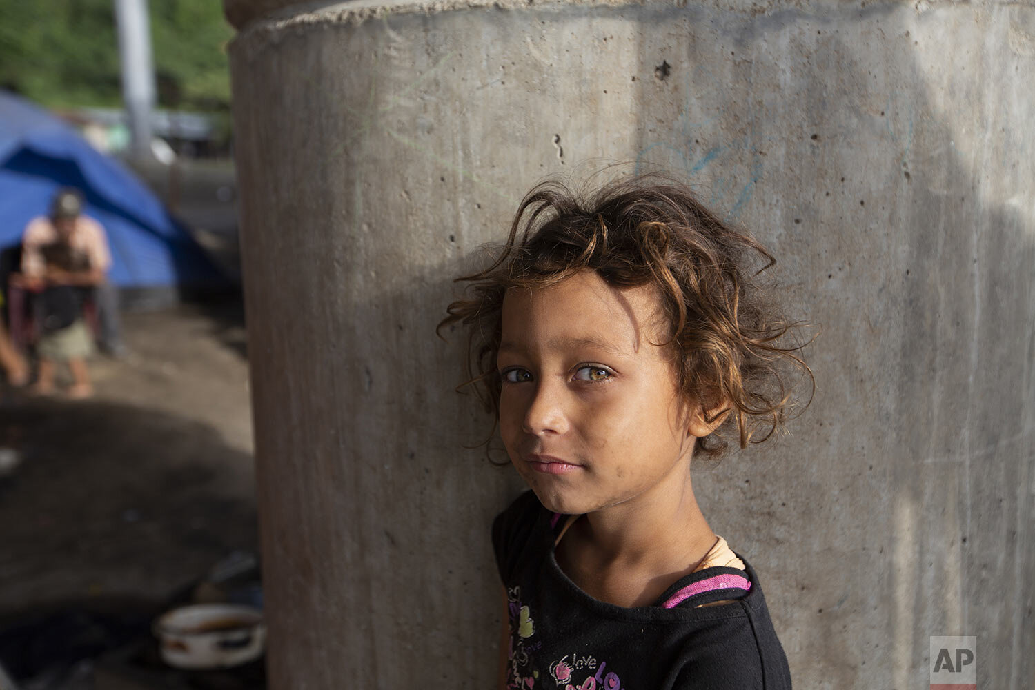  Katerine waits for breakfast cooked by her family under a bridge on the outskirts of San Pedro Sula, Honduras, Jan. 11, 2021, in this photo published in Feb. The 9-year-old has lived under this bridge with her family since they lost their home to la