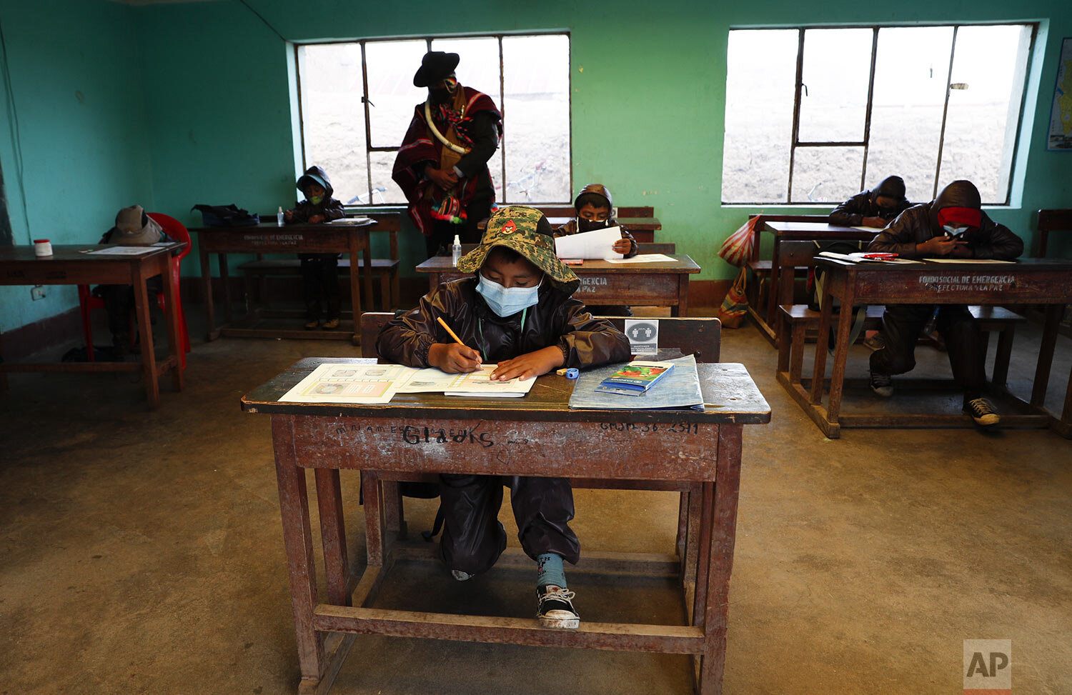  An Aymara Indigenous parent watches over students during the first week back to in-person class with pupils wearing new protective uniforms amid the COVID-19 pandemic near Jesus de Machaca, Bolivia, Feb. 4, 2021. (AP Photo/Juan Karita) 