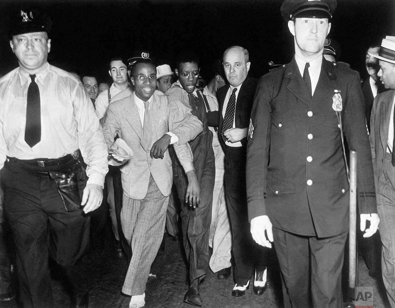 Apparently bewildered by the attention of an uncontrollable crowd, Olen Montgomery, one of the Scottsboro defendants is led through Penn Station upon arrival in New York City, July 26, 1937 by his attorney, Sam Liebowitz while an officer marches ahe