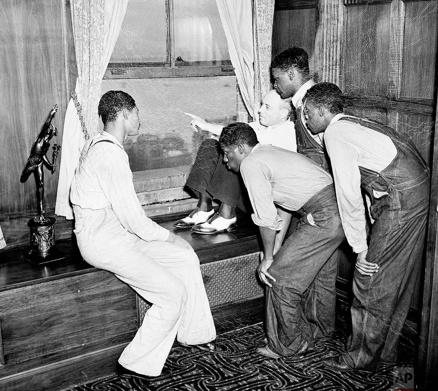  His finger pointing out the Statue of Liberty, Samuel Leibowitz, attorney, holds the attention of the four freed Scottsboro boys now visiting New York City from Alabama, July 26, 1937.   While Eugene Williams sits at left, and  the defendants cluste