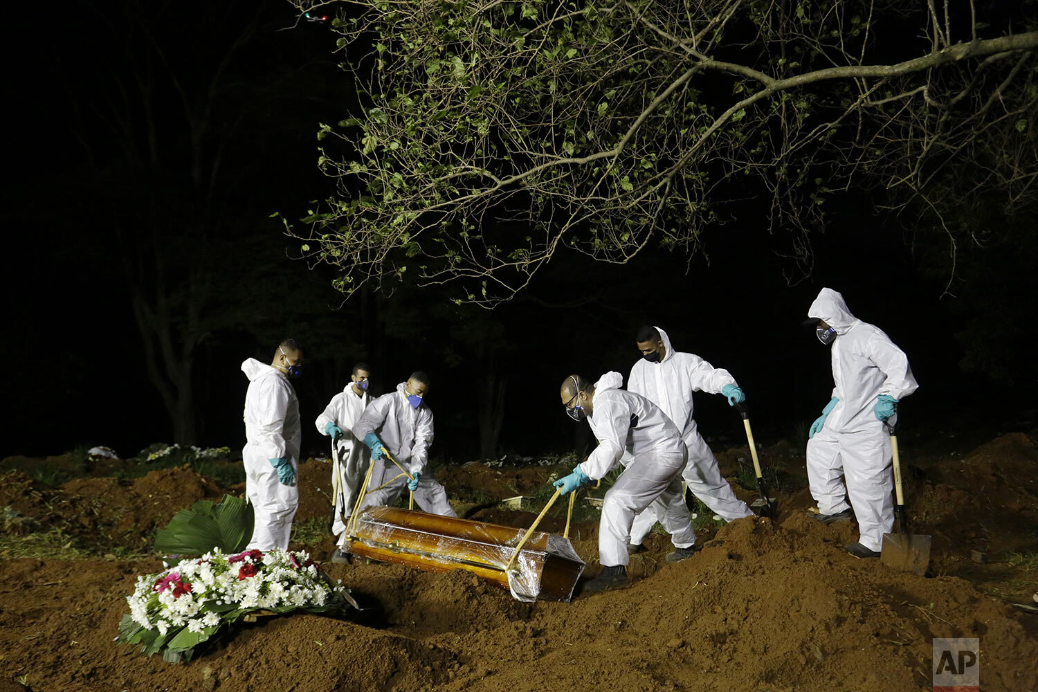 Cemetery workers lower the coffin of a COVID-19 victim into a grave at the Vila Formosa cemetery at night in Sao Paulo, Brazil, March 31, 2021. (AP Photo/Nelson Antoine)