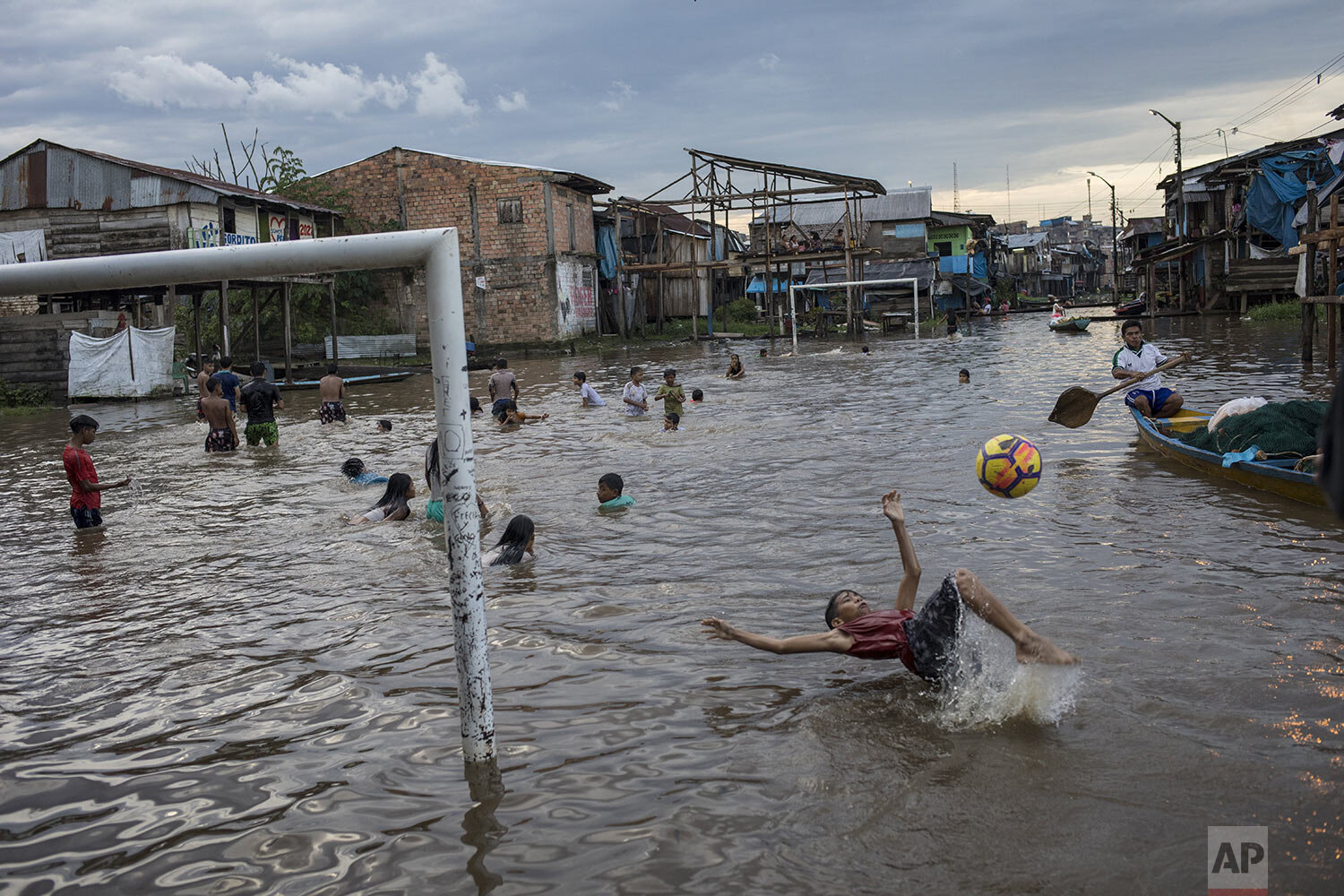 A boy bicycle kicks a ball in a flooded area of the Belen community in Iquitos, Peru, March 20, 2021. (AP Photo/Rodrigo Abd)