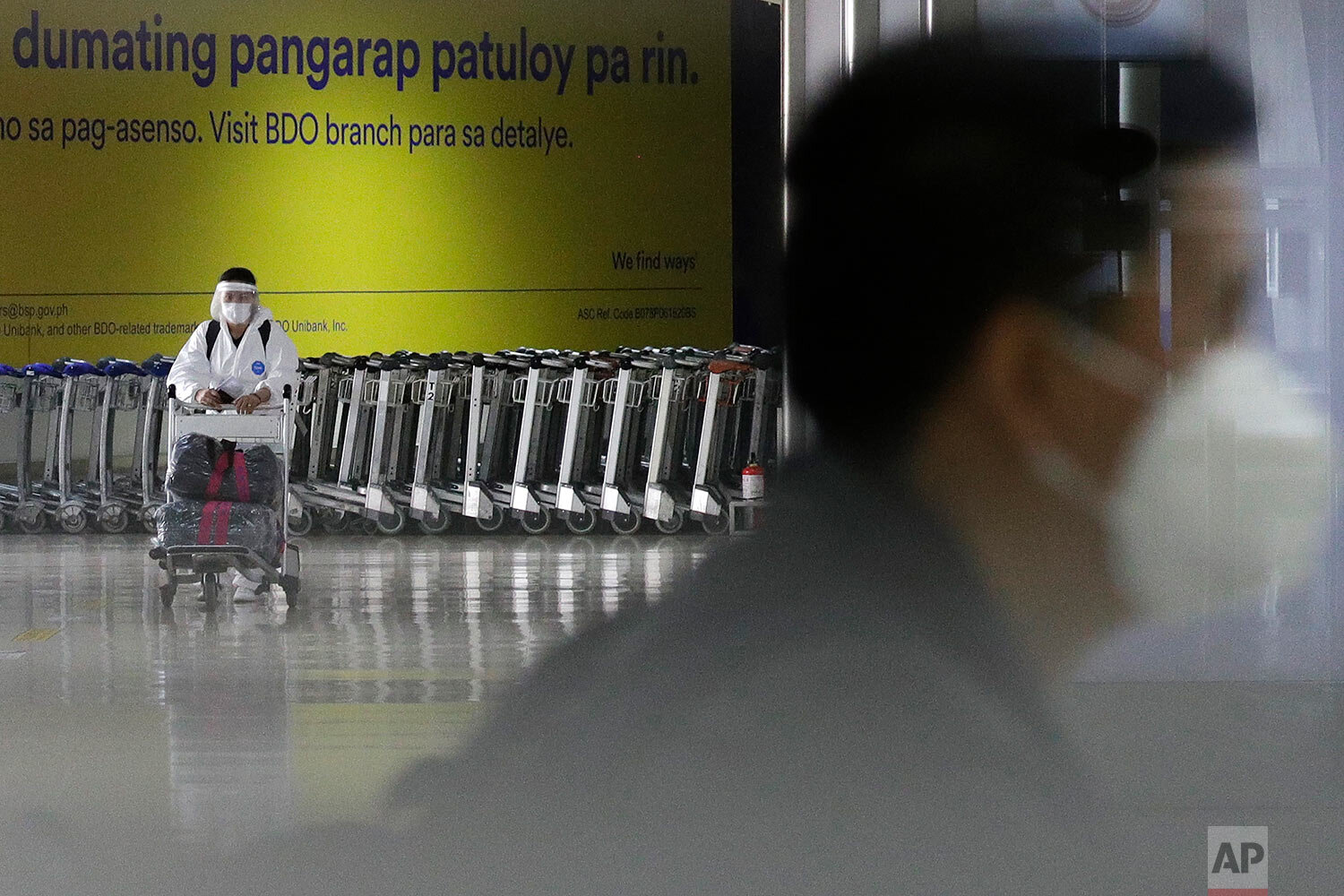  A woman wearing a protective suit pushes a cart at the arrival area of Manila's International Airport, Philippines on Wednesday, March 17, 2021.  (AP Photo/Aaron Favila) 