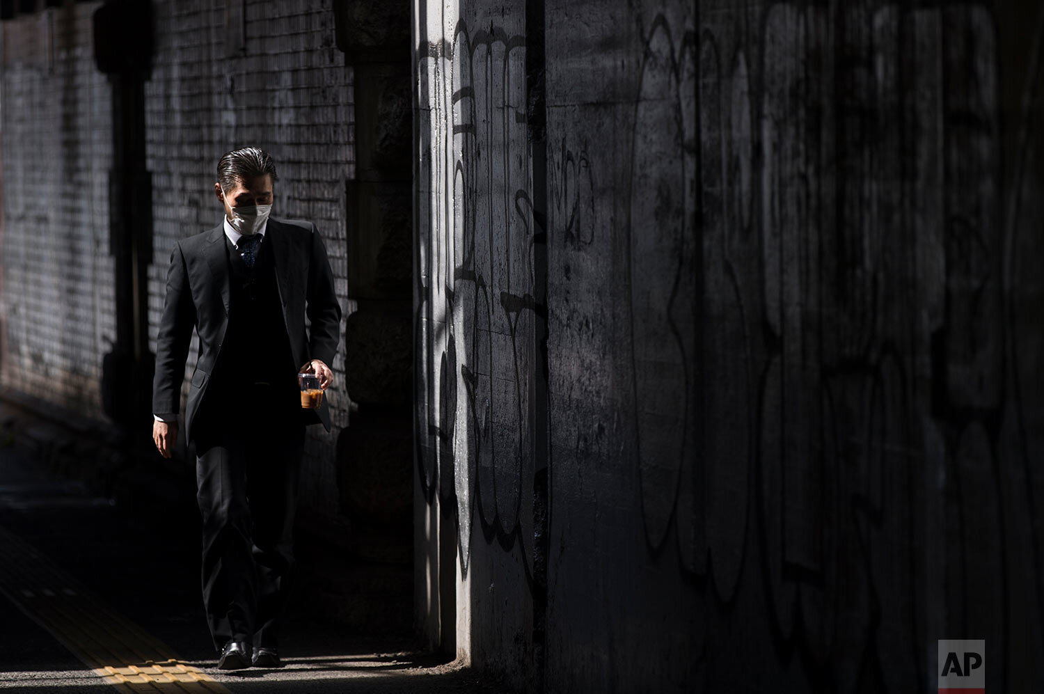  A man wearing a face mask walks on a street during lunchtime in Tokyo on Thursday, March 4, 2021. (AP Photo/Hiro Komae) 