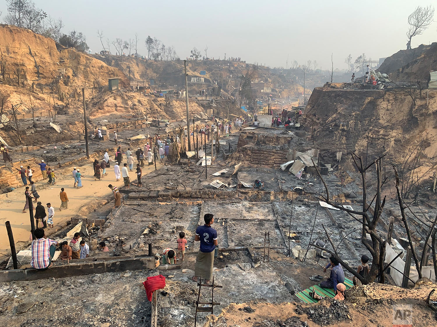  Rohingya refugees look at the remains of Monday's fire at the Rohingya refugee camp in Balukhali, southern Bangladesh, Tuesday, March 23, 2021. (AP Photo/ Shafiqur Rahman) 