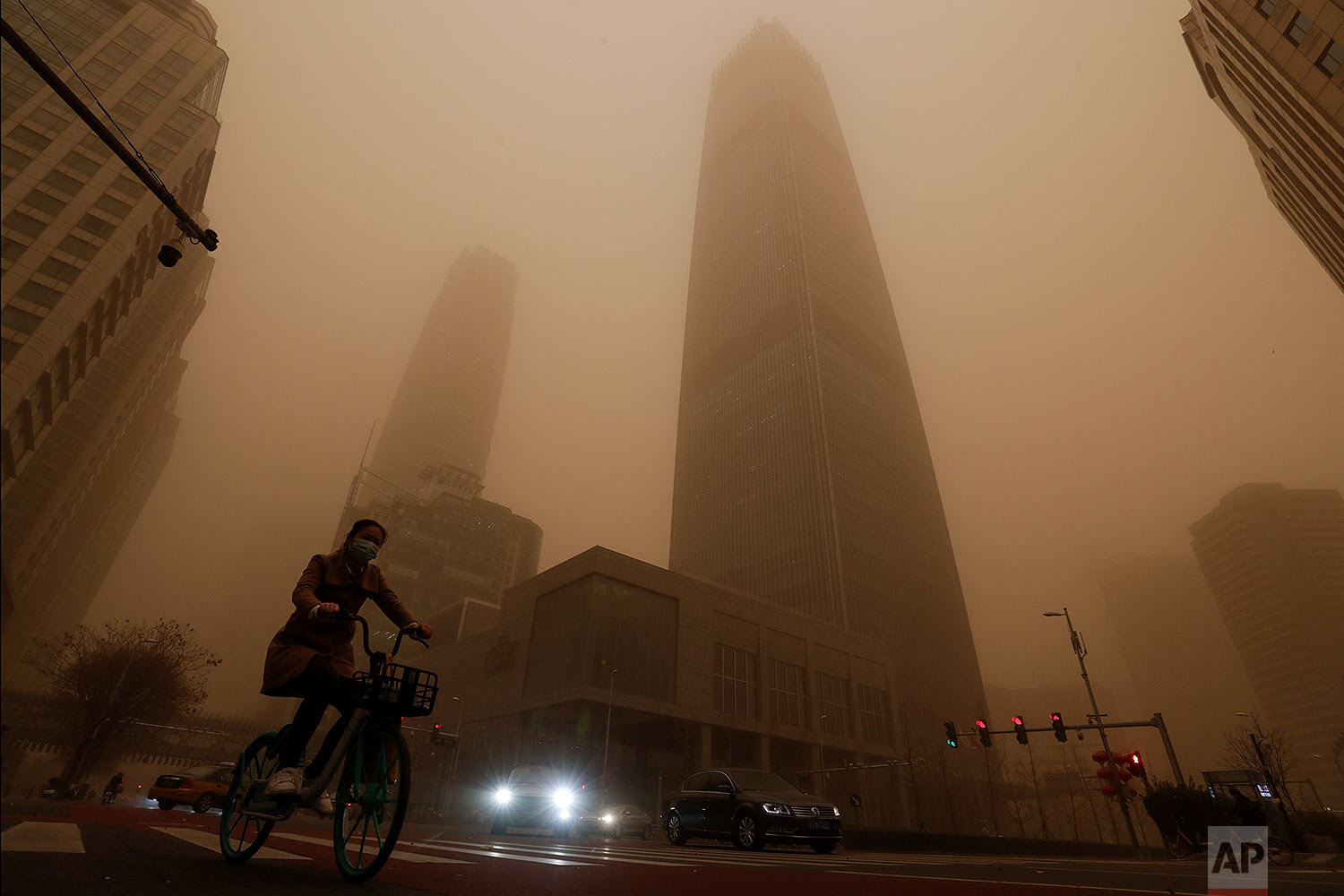  A cyclist and motorists move past office buildings amid a sandstorm during the morning rush hour in the central business district in Beijing, Monday, March 15, 2021.  (AP Photo/Andy Wong) 