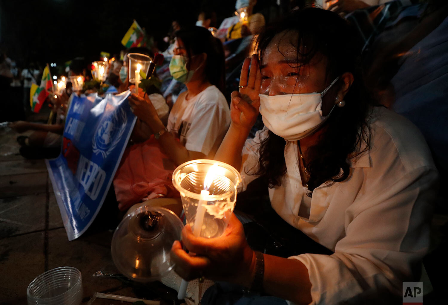  Myanmar nationals living in Thailand participate in a candle light vigil gesture with a three-finger sign of resistance against the Myanmar military coup in front of the United Nations building in Bangkok, Thailand, Thursday, March 4, 2021. (AP Phot