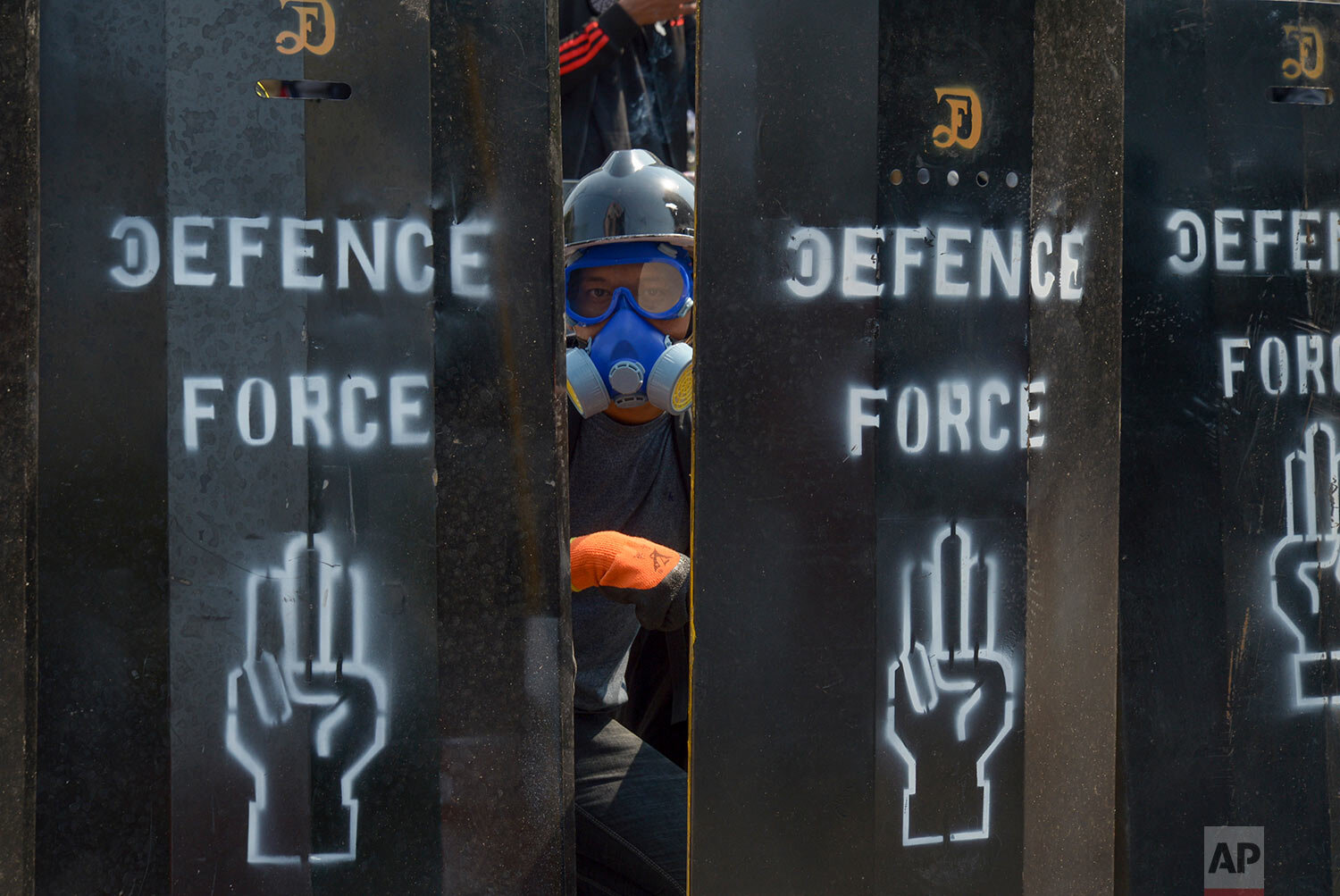  An anti-coup protester peaks out from a makeshift barricades in Yangon, Myanmar Thursday, March 11, 2021. (AP Photo) 