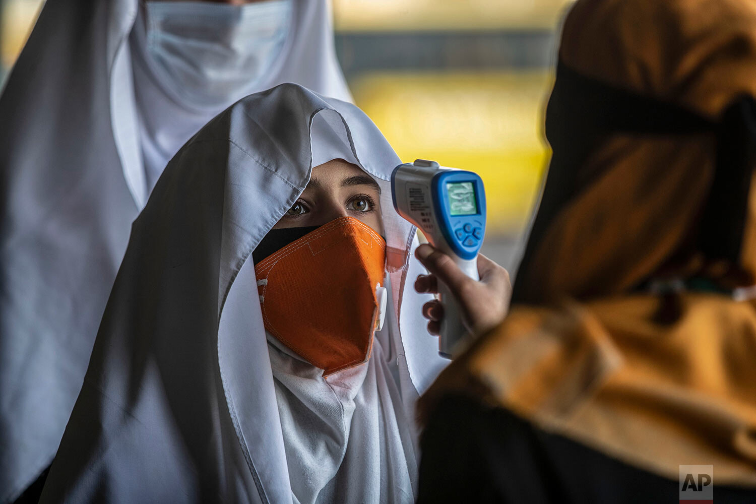  A staff member checks the temperature of students as they arrive to attend their school in Srinagar, Indian controlled Kashmir, Monday, March 15, 2021. (AP Photo/Mukhtar Khan) 