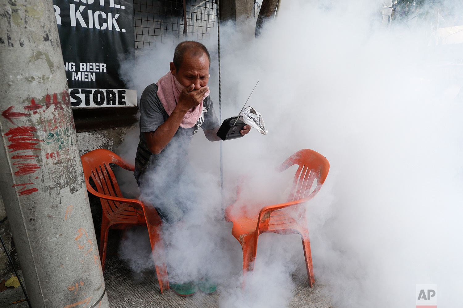  A resident holds his nose and portable radio as he tries to avoid the disinfectants used on their village as a precaution against the spread of COVID-19 in Manila, Philippines on Monday, March 15, 2021. (AP Photo/Aaron Favila) 