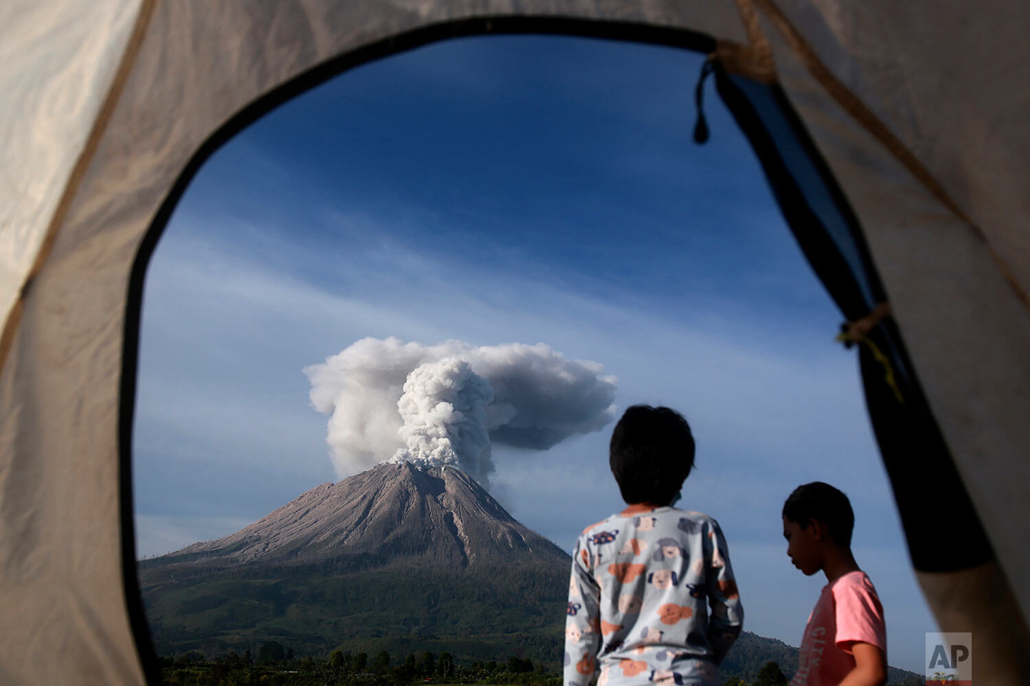  Campers are seen from the opening of a tent as they watch Mount Sinabung erupting in Karo, North Sumatra, Indonesia, Thursday, March 11, 2021. (AP Photo/Binsar Bakkara) 
