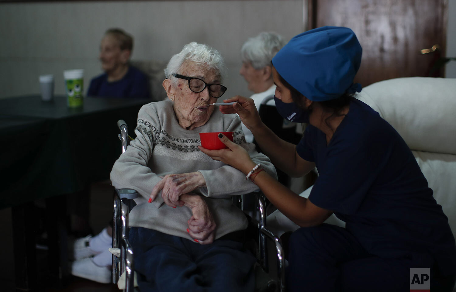 Nurse Rocio Lescano feeds Dora Amestoy her breakfast at the Reminiscencias residence for the elderly in Tandil, Argentina, Monday, April 5, 2021. (AP Photo/Natacha Pisarenko) 