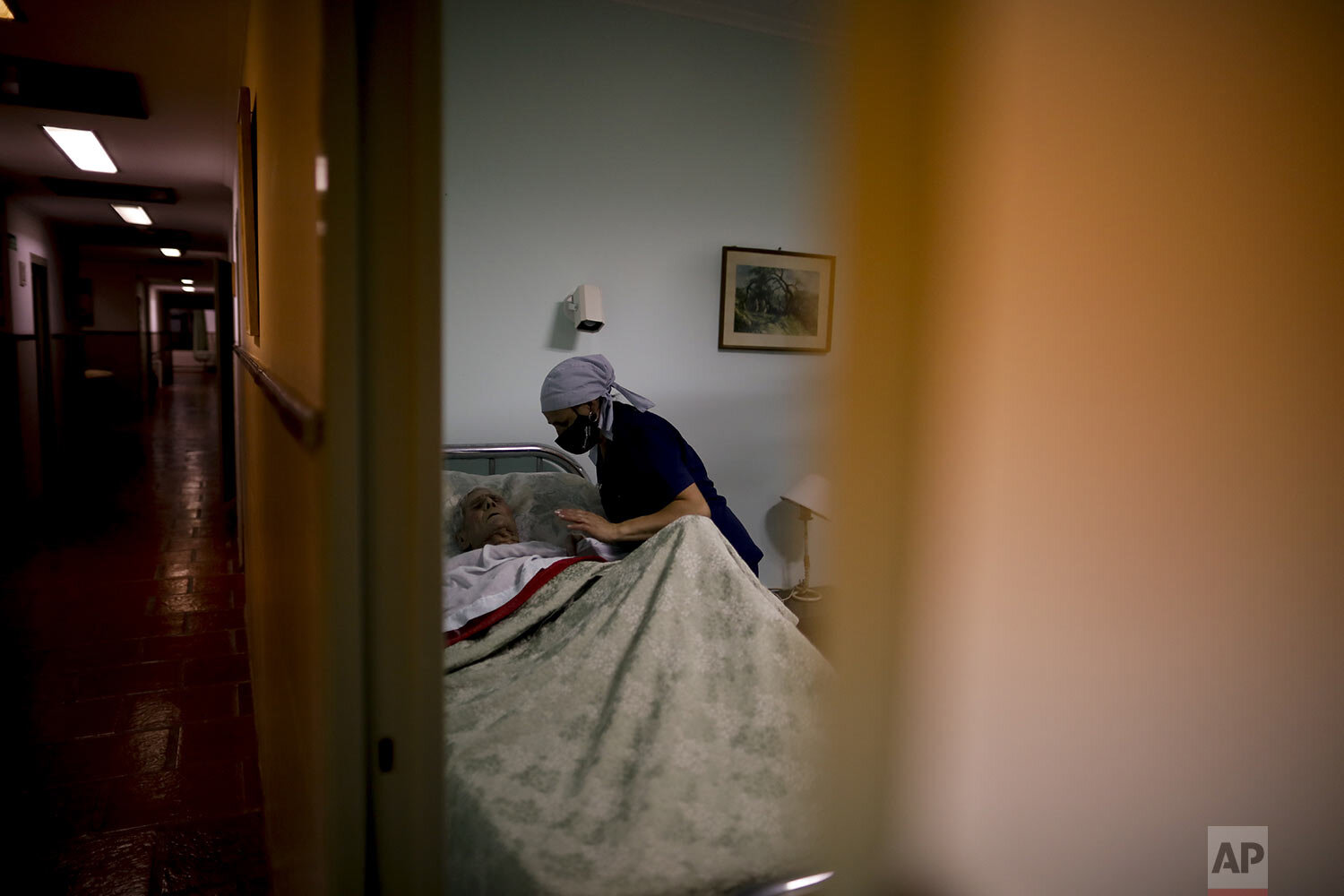  Victor Tripiana, 86, is put to bed by a nurse at the Reminiscencias residence for the elderly in Tandil, Argentina, Sunday, April 4, 2021.  (AP Photo/Natacha Pisarenko) 