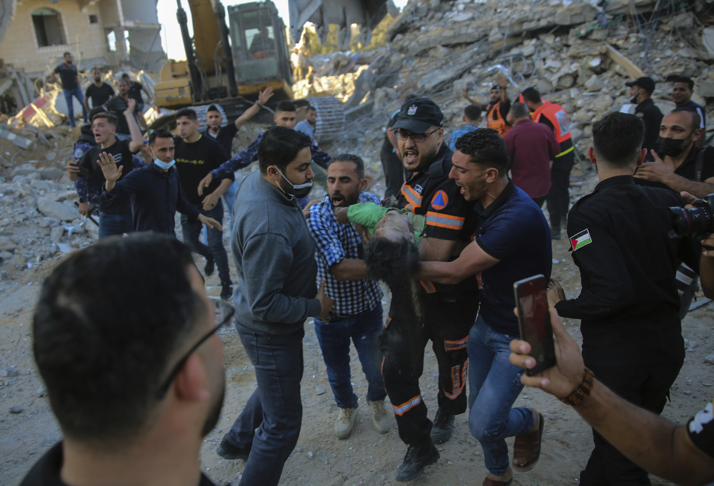  Palestinians carry the body of a child found in the rubble of a house belonging to the Tanani family, that was destroyed in Israeli airstrikes in town of Beit Lahiya, northern Gaza Strip, Thursday, May 13, 2021. (AP Photo/Abdel Kareem Hana) 