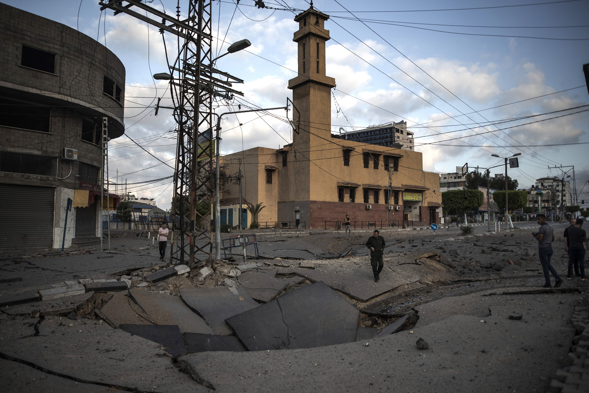  Palestinians walk along a destroyed road following Israeli airstrikes on Gaza City, Thursday, May 13, 2021. (AP Photo/Khalil Hamra) 