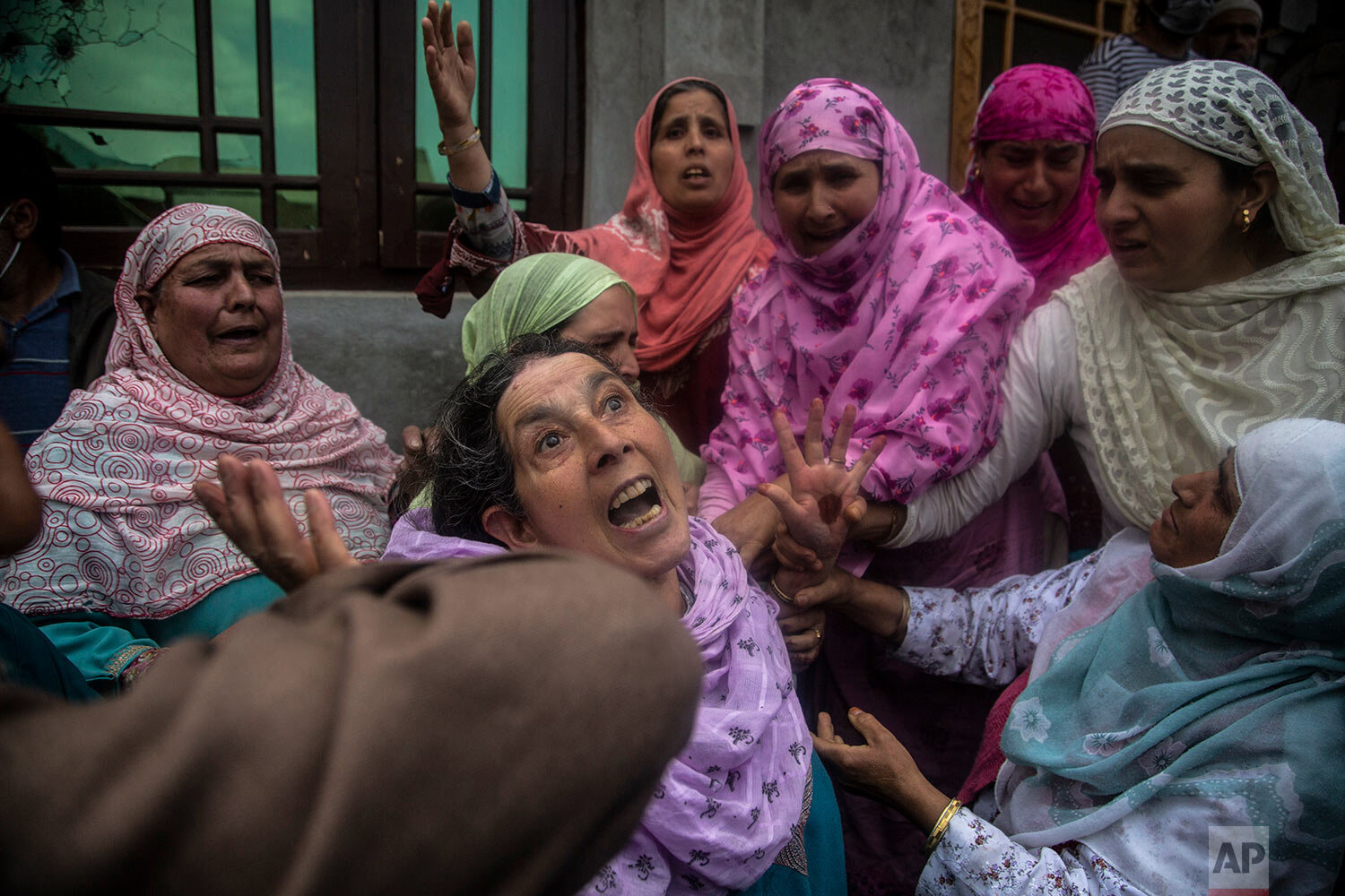  An elderly Kashmiri woman, center, reacts to the news of the killing of two suspects rebels after a gun battle between government forces and suspected rebels on the outskirts of Srinagar, Indian controlled Kashmir, Monday, May 17, 2021. (AP Photo/Mu